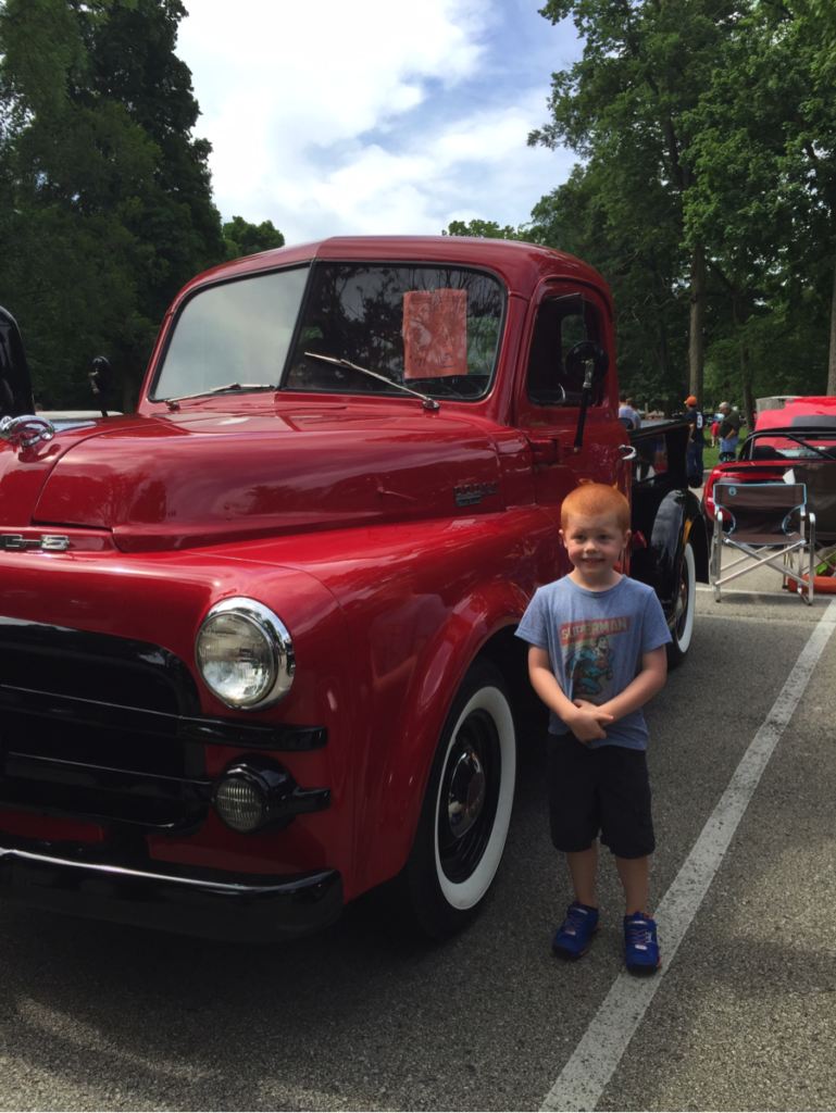 little boy next to classic red truck