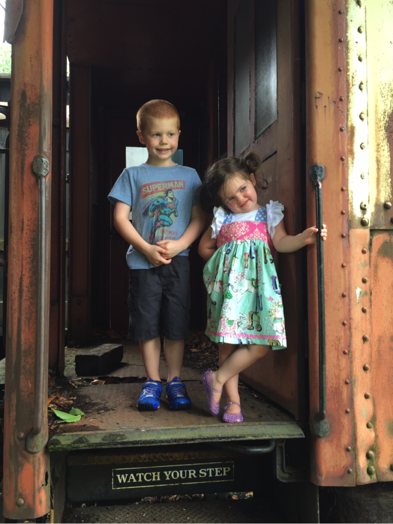photo of young boy with his little sister standing in doorway of old historic train